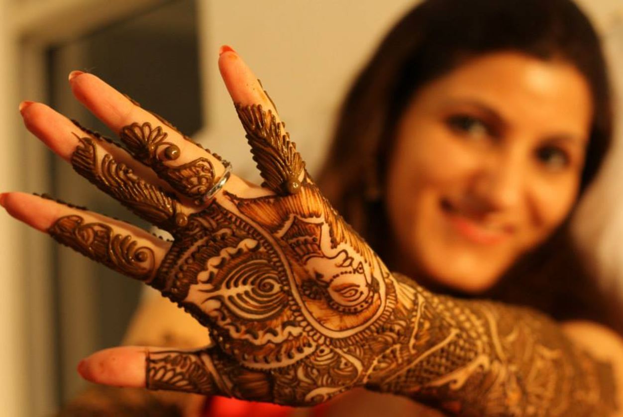 Indian Hindu Couple Wearing Traditional Indian Dress And Floral Garland,  Holding Each Other Hands During Their Marriage Promising Blissful Life.  Beautiful Henna Mehndi Art And Bangles On Birde Hands Stock Photo, Picture